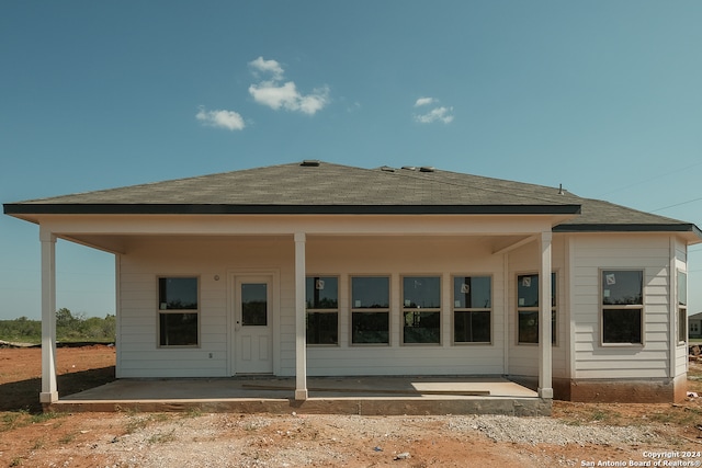 rear view of house featuring roof with shingles and a patio