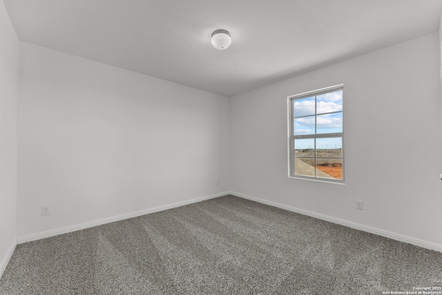 unfurnished room featuring dark carpet and baseboards