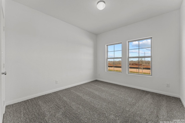 unfurnished room featuring dark colored carpet and baseboards