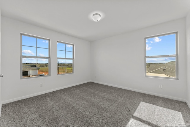 unfurnished room featuring dark colored carpet and baseboards