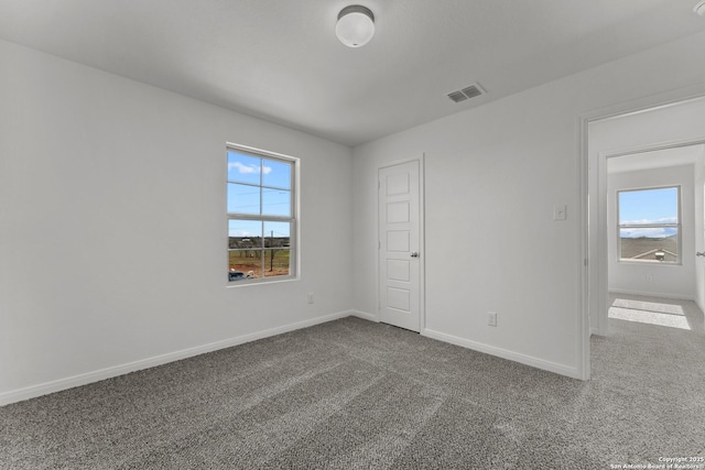 empty room featuring baseboards, visible vents, and carpet flooring