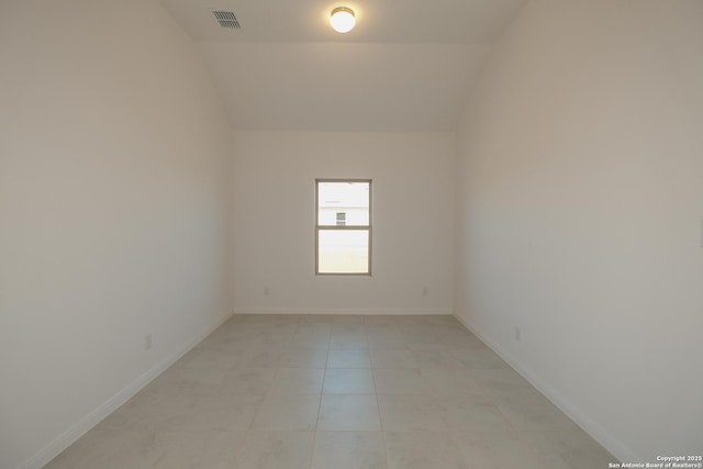 spare room with lofted ceiling, visible vents, and baseboards