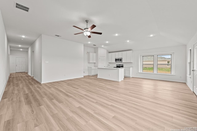 unfurnished living room featuring vaulted ceiling, light wood-style flooring, visible vents, and a ceiling fan