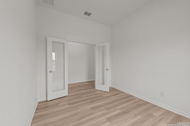 unfurnished room with light wood-style flooring, visible vents, and baseboards