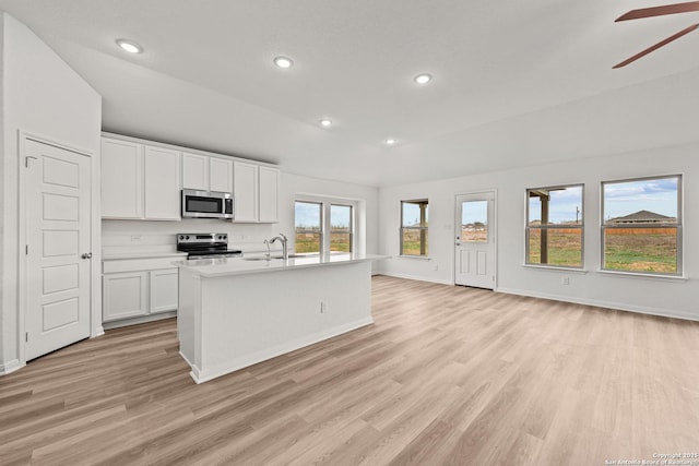 kitchen featuring white cabinetry, a center island with sink, light hardwood / wood-style flooring, ceiling fan, and stainless steel appliances