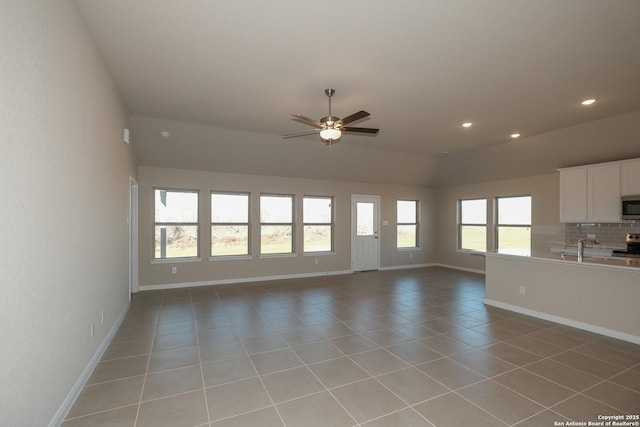 unfurnished living room with sink, light tile patterned floors, and ceiling fan