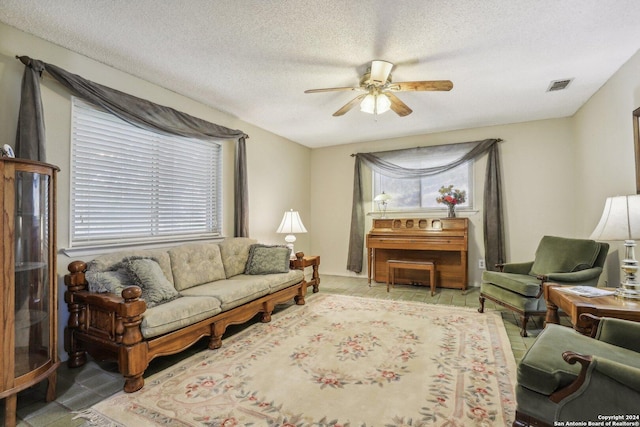 living area featuring a ceiling fan, visible vents, and a textured ceiling