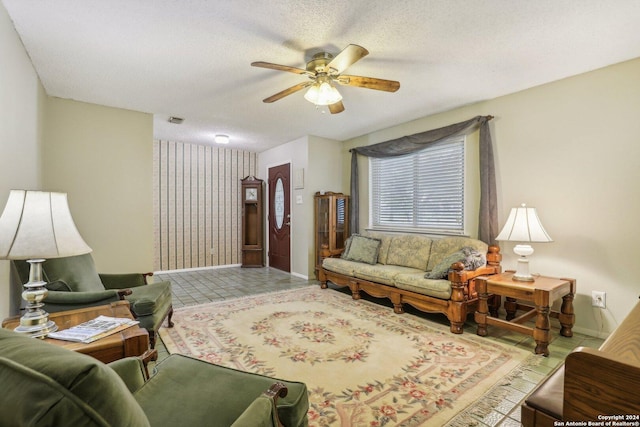 living room featuring a ceiling fan, visible vents, baseboards, and a textured ceiling