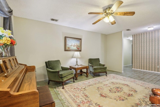 living area with light tile patterned floors, ceiling fan, visible vents, and a textured ceiling