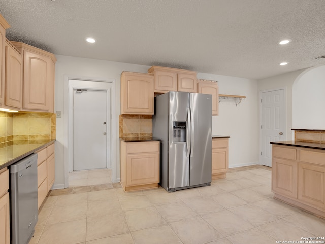 kitchen with light tile patterned floors, stainless steel appliances, tasteful backsplash, and light brown cabinets