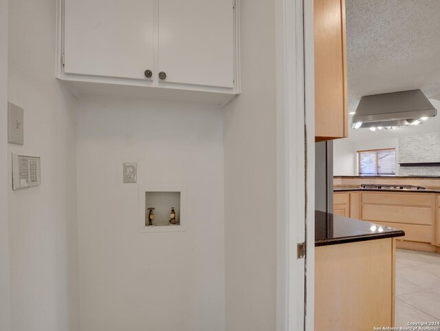 washroom featuring light tile patterned floors, hookup for a washing machine, and a textured ceiling