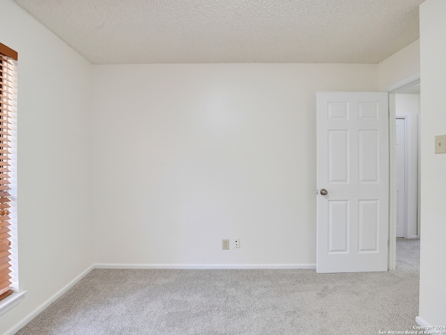 unfurnished room with a textured ceiling and light carpet