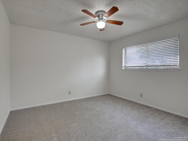 carpeted empty room with ceiling fan and a textured ceiling