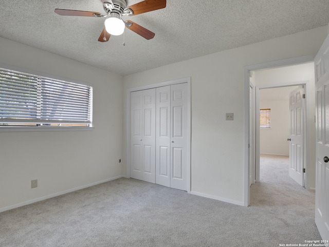 unfurnished bedroom with ceiling fan, light colored carpet, a closet, and multiple windows