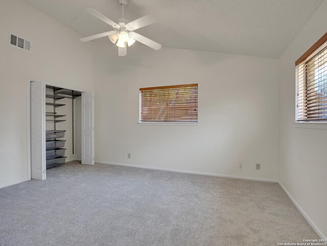 unfurnished bedroom featuring ceiling fan, light carpet, a closet, and high vaulted ceiling