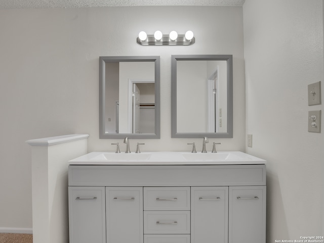 bathroom with dual bowl vanity and a textured ceiling