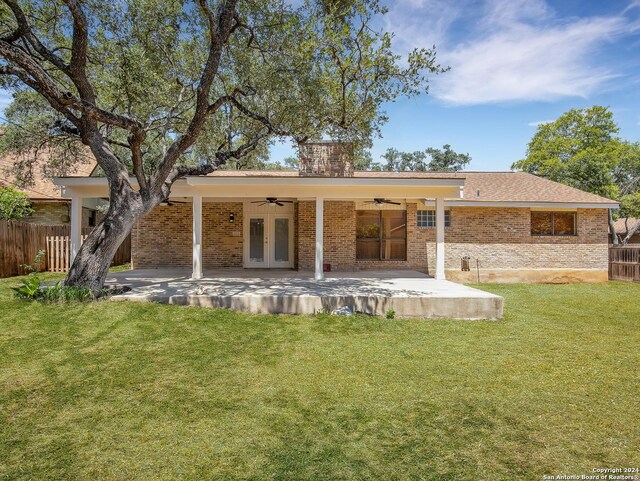 rear view of house with ceiling fan, a patio, french doors, and a lawn