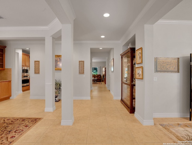 hall with ornate columns, crown molding, and light tile patterned floors