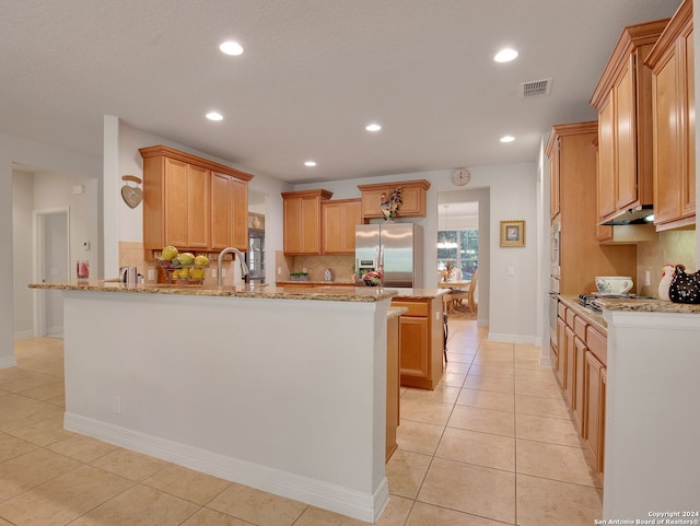 kitchen featuring decorative backsplash, appliances with stainless steel finishes, light stone countertops, kitchen peninsula, and light tile patterned flooring