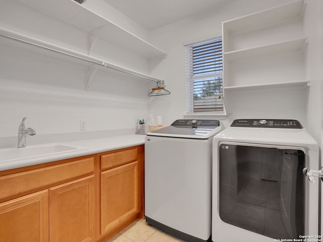 clothes washing area featuring sink, light tile patterned floors, cabinets, and independent washer and dryer