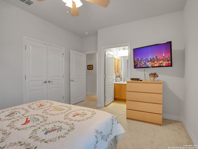 bedroom featuring ceiling fan, light carpet, a closet, and connected bathroom