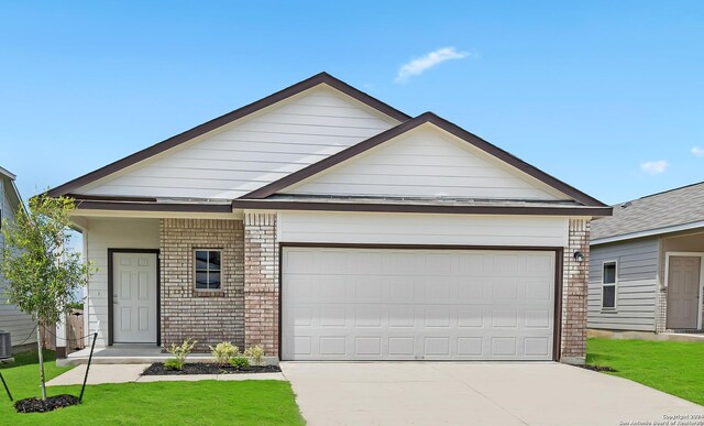 view of front of house with a front lawn, central AC, and a garage