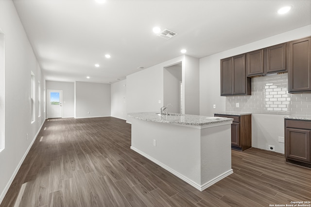 kitchen featuring dark hardwood / wood-style flooring, sink, backsplash, and light stone counters