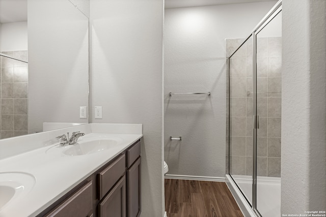 bathroom featuring an enclosed shower, toilet, double sink vanity, and wood-type flooring