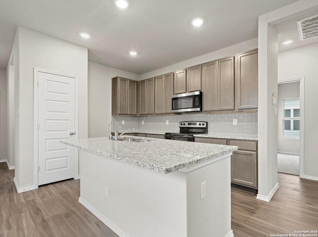 kitchen featuring light hardwood / wood-style floors, stainless steel appliances, a center island with sink, and sink