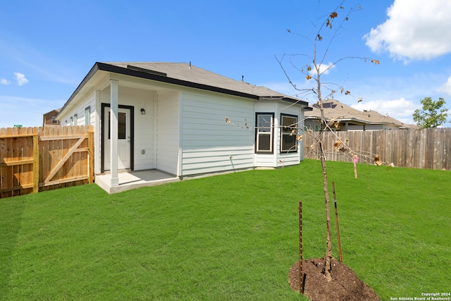 back of property with a lawn and a patio