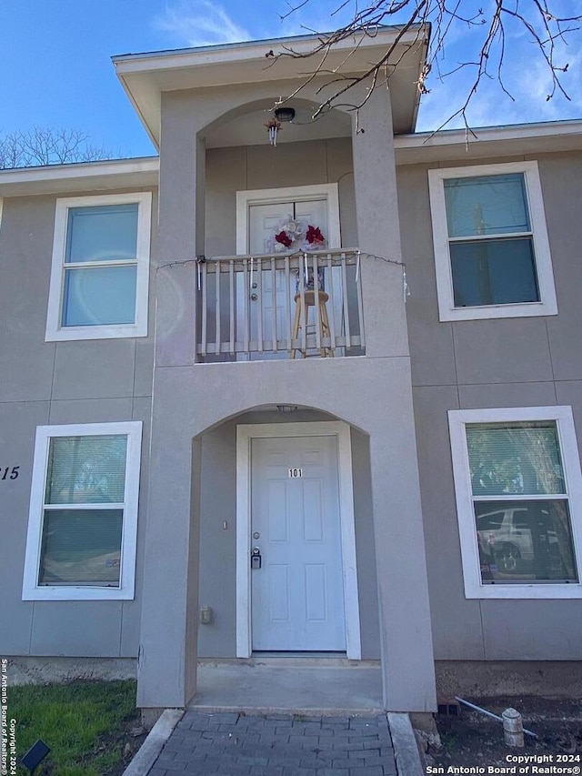 property entrance with stucco siding and a balcony