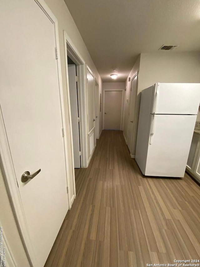 hallway with visible vents and wood finished floors