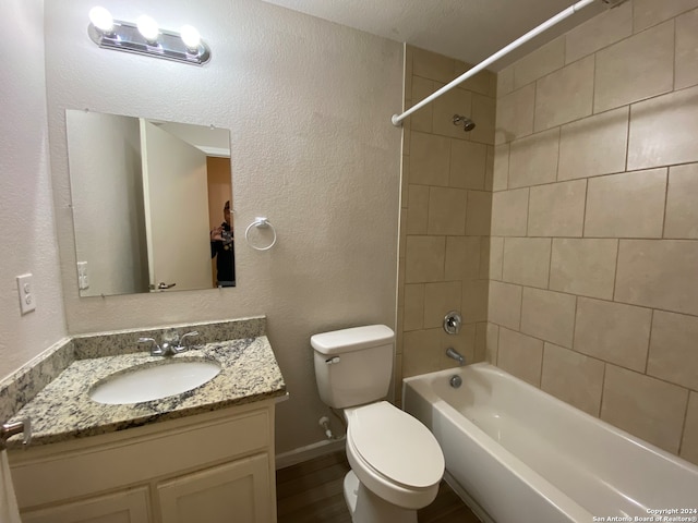 full bathroom with toilet, vanity, hardwood / wood-style floors, a textured ceiling, and tiled shower / bath combo