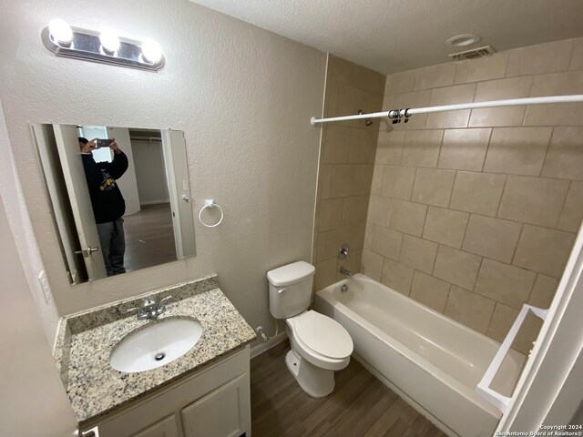 full bathroom with toilet, vanity, hardwood / wood-style floors, a textured ceiling, and tiled shower / bath combo