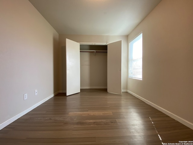 unfurnished bedroom featuring a closet and dark hardwood / wood-style floors