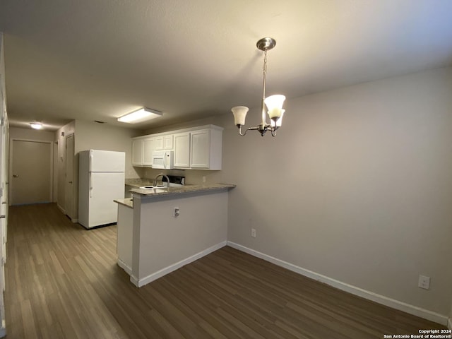 kitchen with white appliances, wood finished floors, baseboards, a sink, and white cabinetry