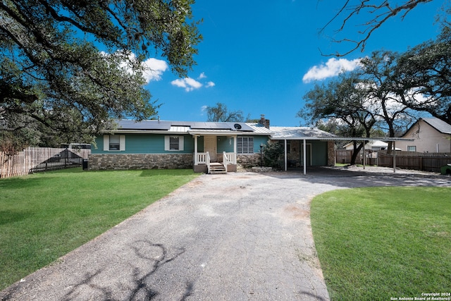 ranch-style home with solar panels, a carport, and a front yard