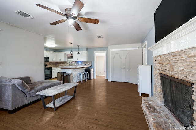 living room with ceiling fan, dark wood-type flooring, and a fireplace