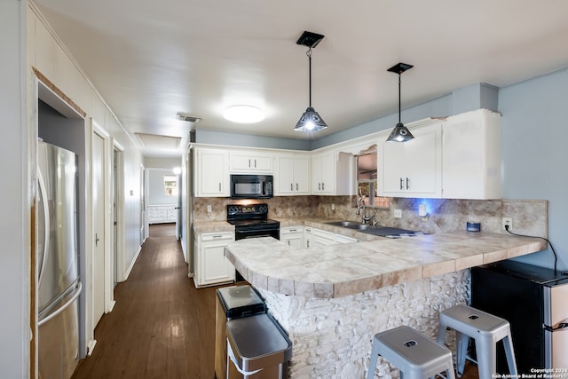 kitchen with black appliances, pendant lighting, kitchen peninsula, dark wood-type flooring, and a breakfast bar