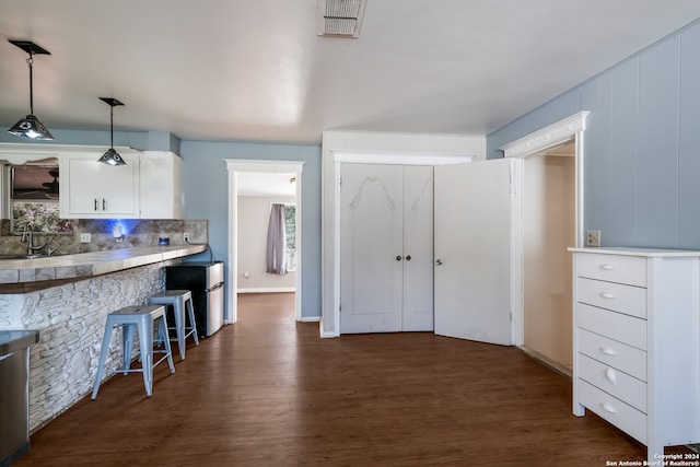 kitchen featuring decorative backsplash, decorative light fixtures, white cabinets, and dark hardwood / wood-style floors