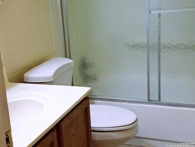 full bathroom with enclosed tub / shower combo, vanity, and toilet