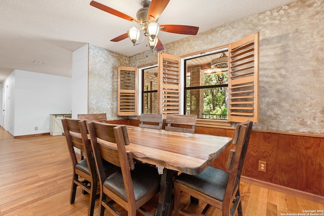 dining room with ceiling fan, light hardwood / wood-style flooring, and a textured ceiling