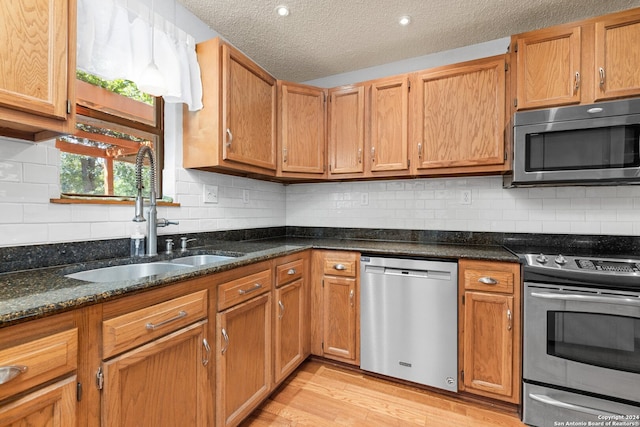 kitchen with stainless steel appliances, light hardwood / wood-style flooring, tasteful backsplash, and a textured ceiling