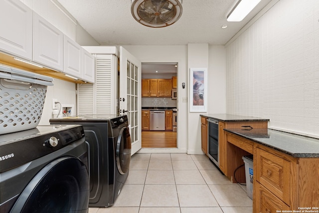 clothes washing area with cabinets, light hardwood / wood-style floors, a textured ceiling, washer and dryer, and beverage cooler