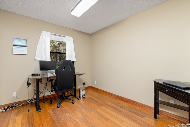 home office with a textured ceiling and light hardwood / wood-style flooring