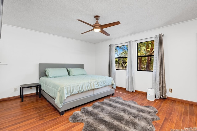 bedroom with ceiling fan, hardwood / wood-style flooring, and a textured ceiling