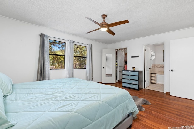 tiled bedroom featuring a textured ceiling, ensuite bath, a spacious closet, a closet, and ceiling fan