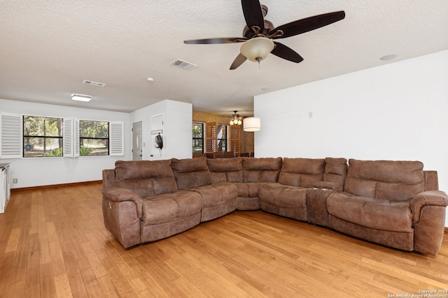 living room with a textured ceiling, ceiling fan, and light wood-type flooring