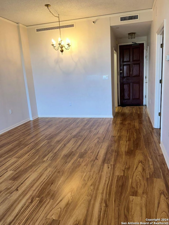 unfurnished room featuring a notable chandelier, a textured ceiling, and hardwood / wood-style floors