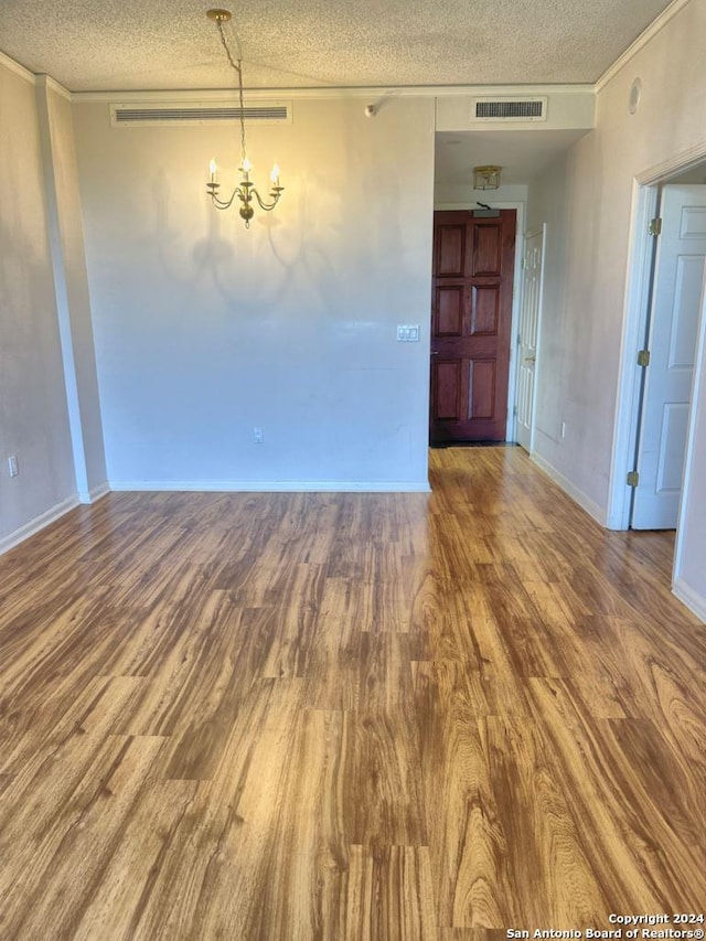 spare room with hardwood / wood-style flooring, a textured ceiling, and a chandelier